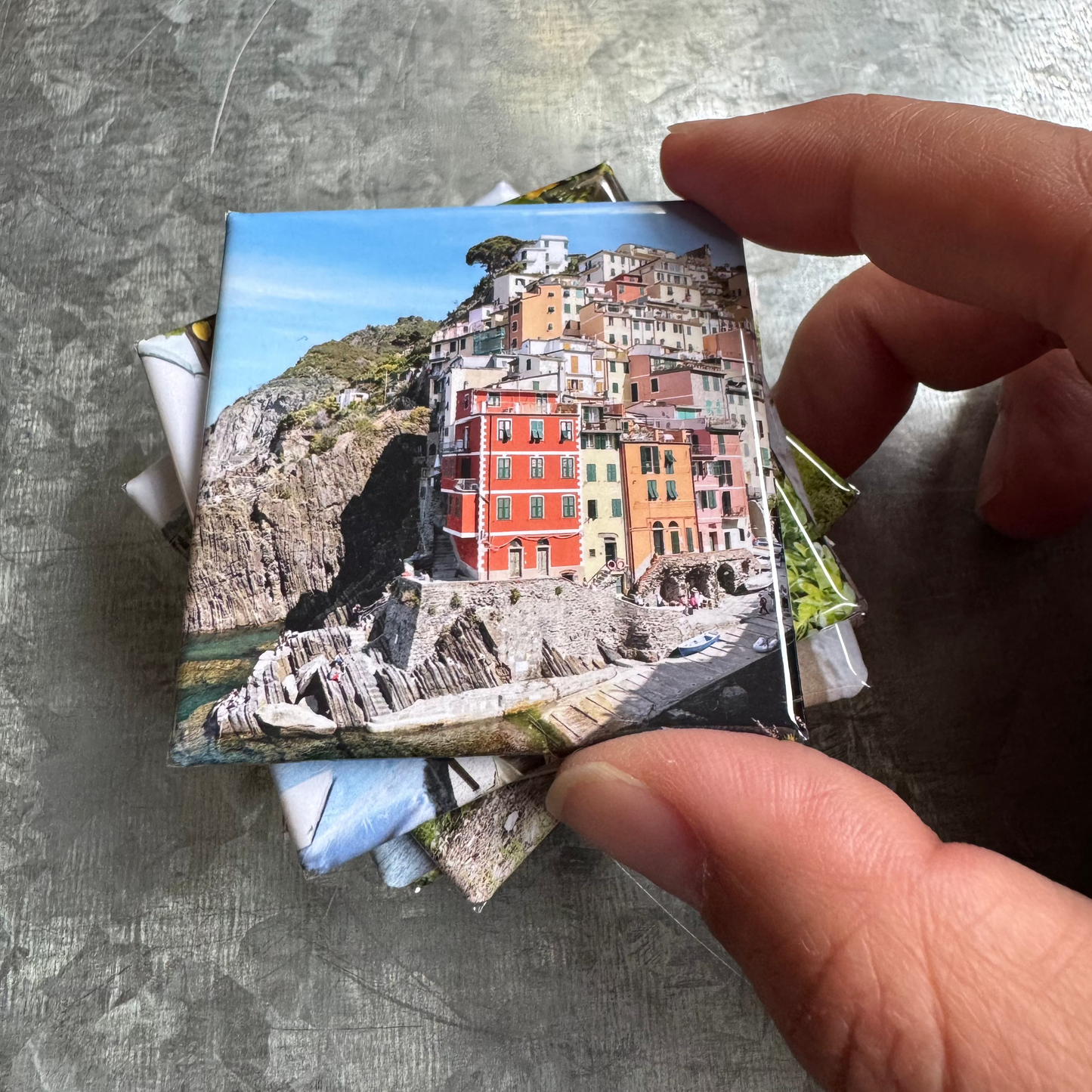 Hand holding a 2x2 handmade photo magnet to show size and smooth finish – Magnetic Momma product detail